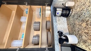 Una cocina con encimera de madera, cafetera y varios utensilios de cocina.