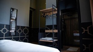A hotel room with a bed, a mirror, a wooden shelf with hanging clothes, and a wardrobe. - ART ROOM One of one Experiences (Rome)