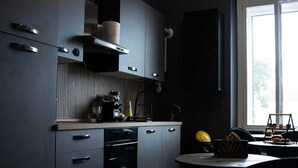 A modern kitchen with dark cabinetry, a built-in oven, and a dining area with a table and chairs. - ART ROOM One of one Experiences (Rome)