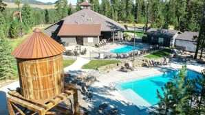 Un resort con una piscina grande, mobiliario exterior y una torre de agua de madera.