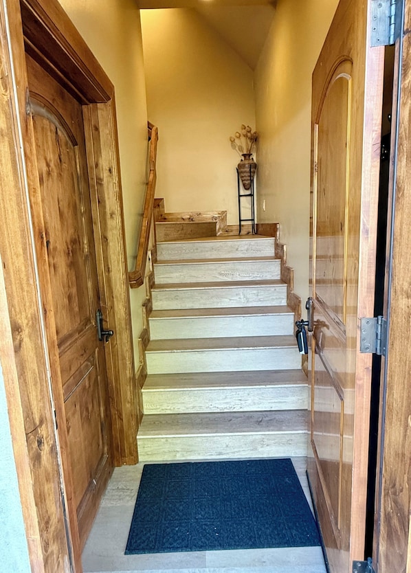 A wooden staircase leading to a room with a door on the left and a door on the right.