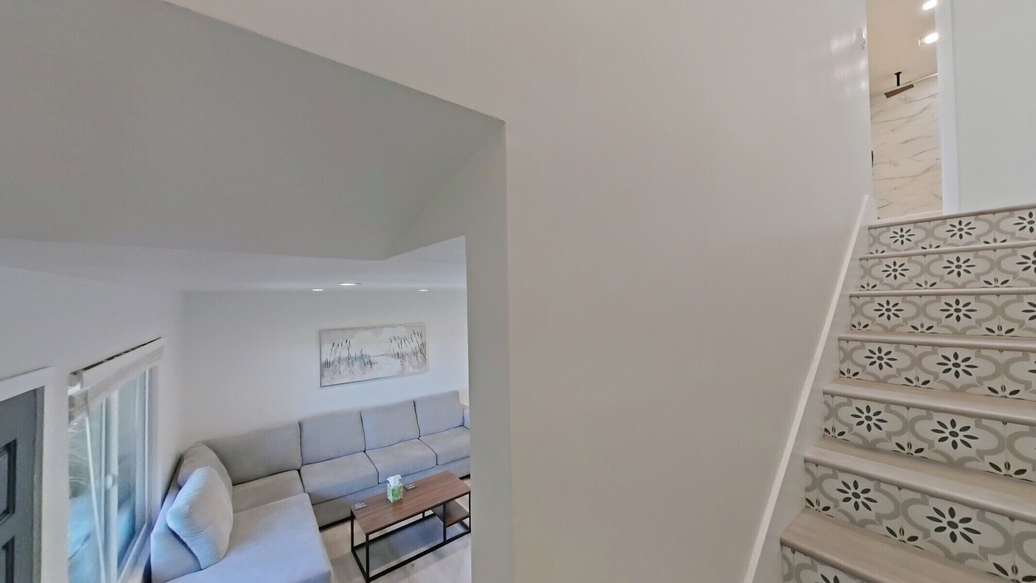 A modern living room with a sofa, coffee table, and a painting on the wall.