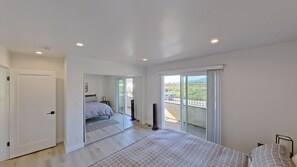 A bedroom with a bed, a sliding glass door to a balcony, and a white door. - Beachside Bliss in Carpinteria Blocks to the Beach, Mountain Views (Carpinteria)