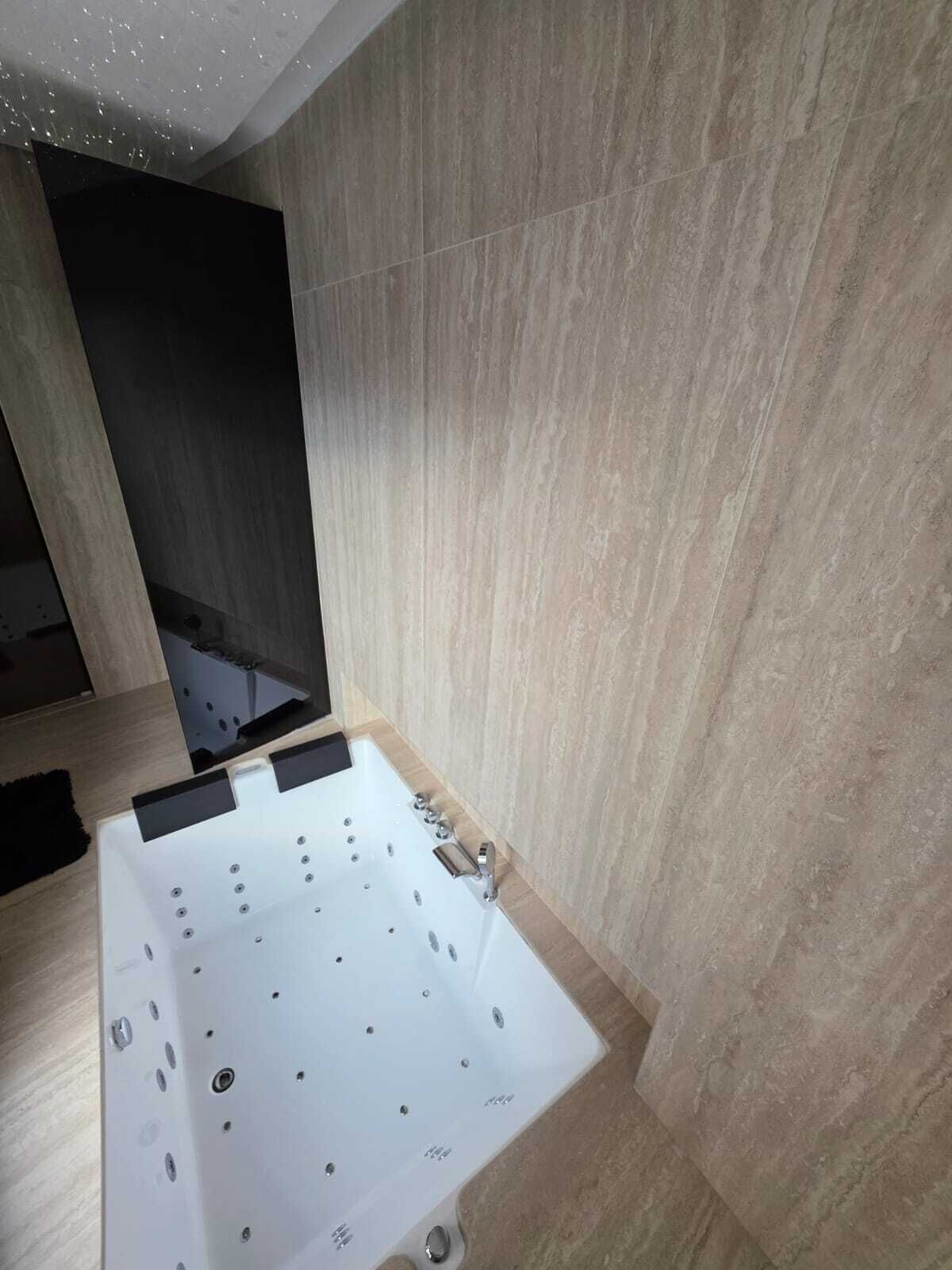 Une salle de bain moderne avec une grande baignoire, un plancher en bois et un mur carrelé.
