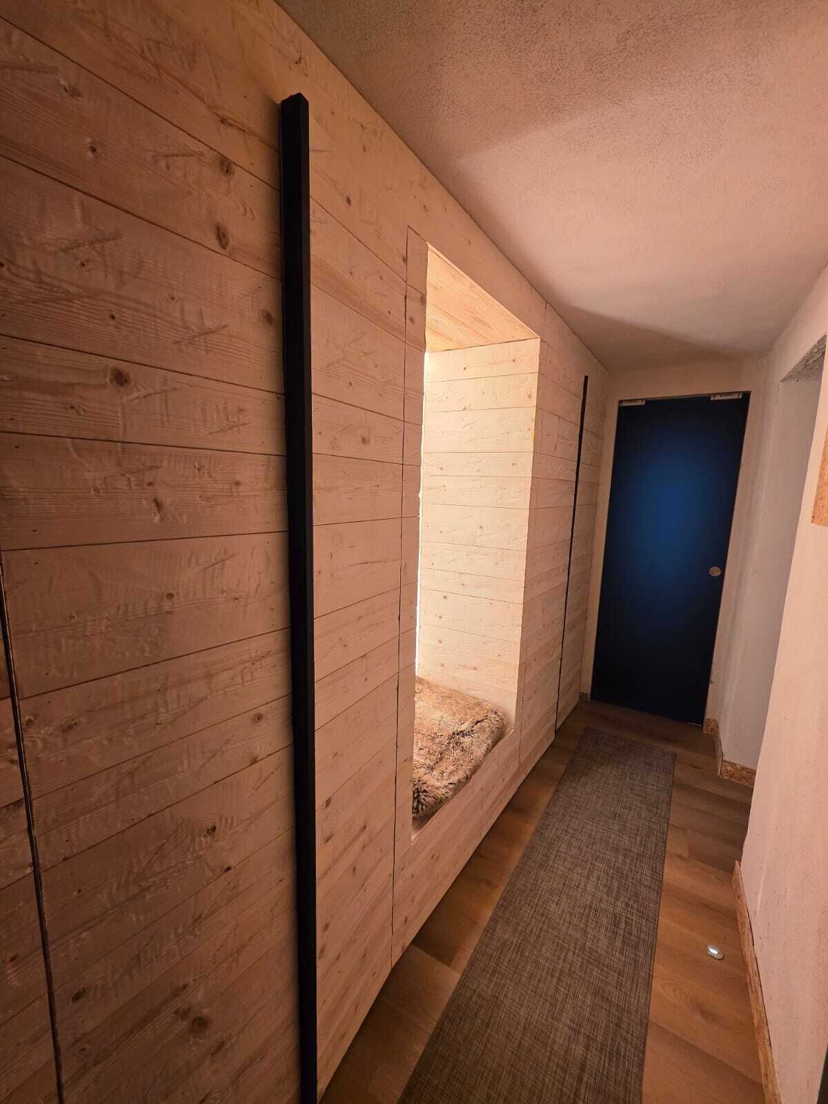 Un pasillo con paredes de madera, una puerta azul y suelo cubierto de alfombra.