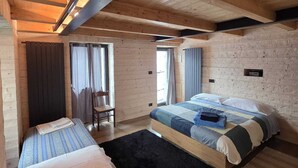 A cozy bedroom with two beds, wooden beams, and a black rug. - Muranche loft S1, fined and elegant apartment with Jacuzzi (Pâquier)