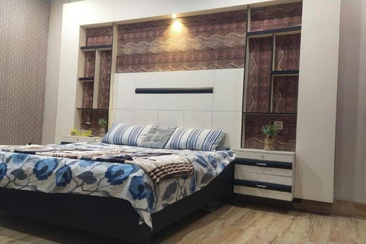 A bedroom with a bed, bedside tables, a nightstand, and a built-in shelving unit with decorative patterns.
