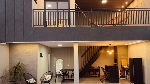 A modern two-story building with a balcony, a staircase, a pool, and a dining area. - House with Private Pool and Gourmet Area (Cascavel)