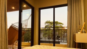 A bedroom with a large bed, a hammock, and a balcony with a view of the outside. - House with Private Pool and Gourmet Area (Cascavel)
