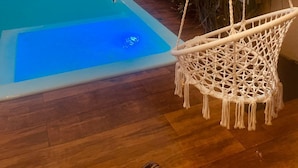 A pool with a hanging chair and plants. - House with Private Pool and Gourmet Area (Cascavel)