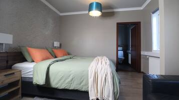 A bedroom with a bed, nightstands, a lamp, a chair, and a window.