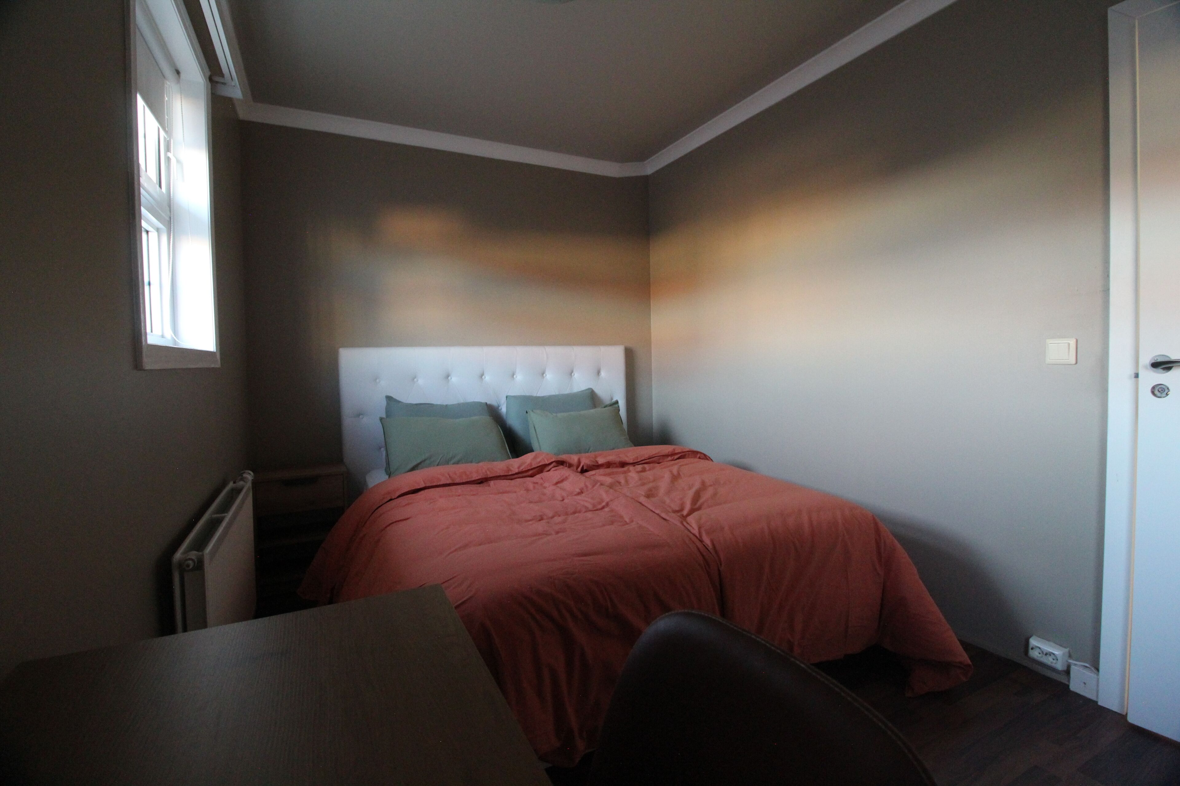 A bedroom with a bed, a nightstand, and a chair.