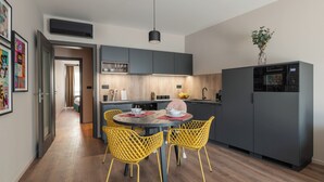 A modern kitchen with a central island, yellow chairs, and grey cabinets.