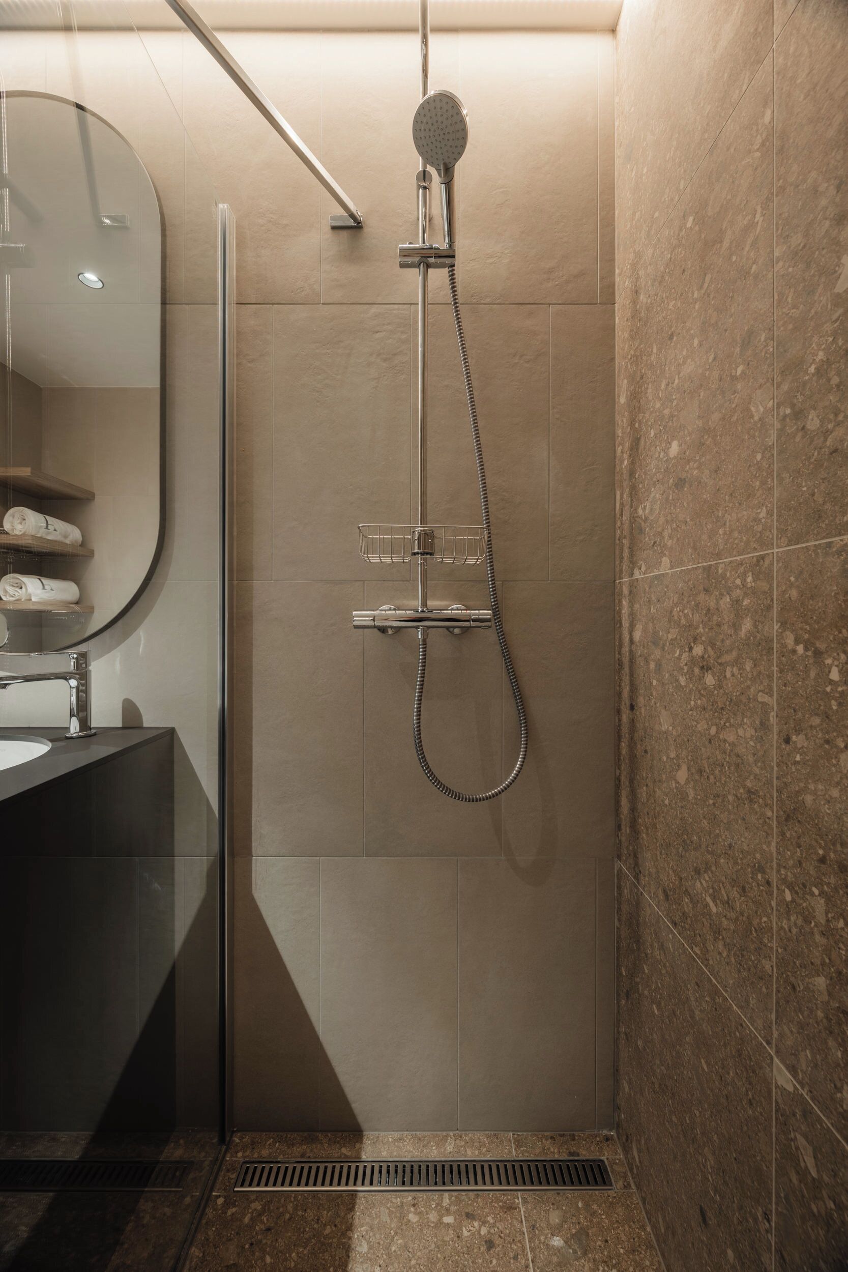 Une salle de bain moderne avec une douche à parois de verre, un lavabo avec un miroir et un porte-serviettes avec des serviettes.