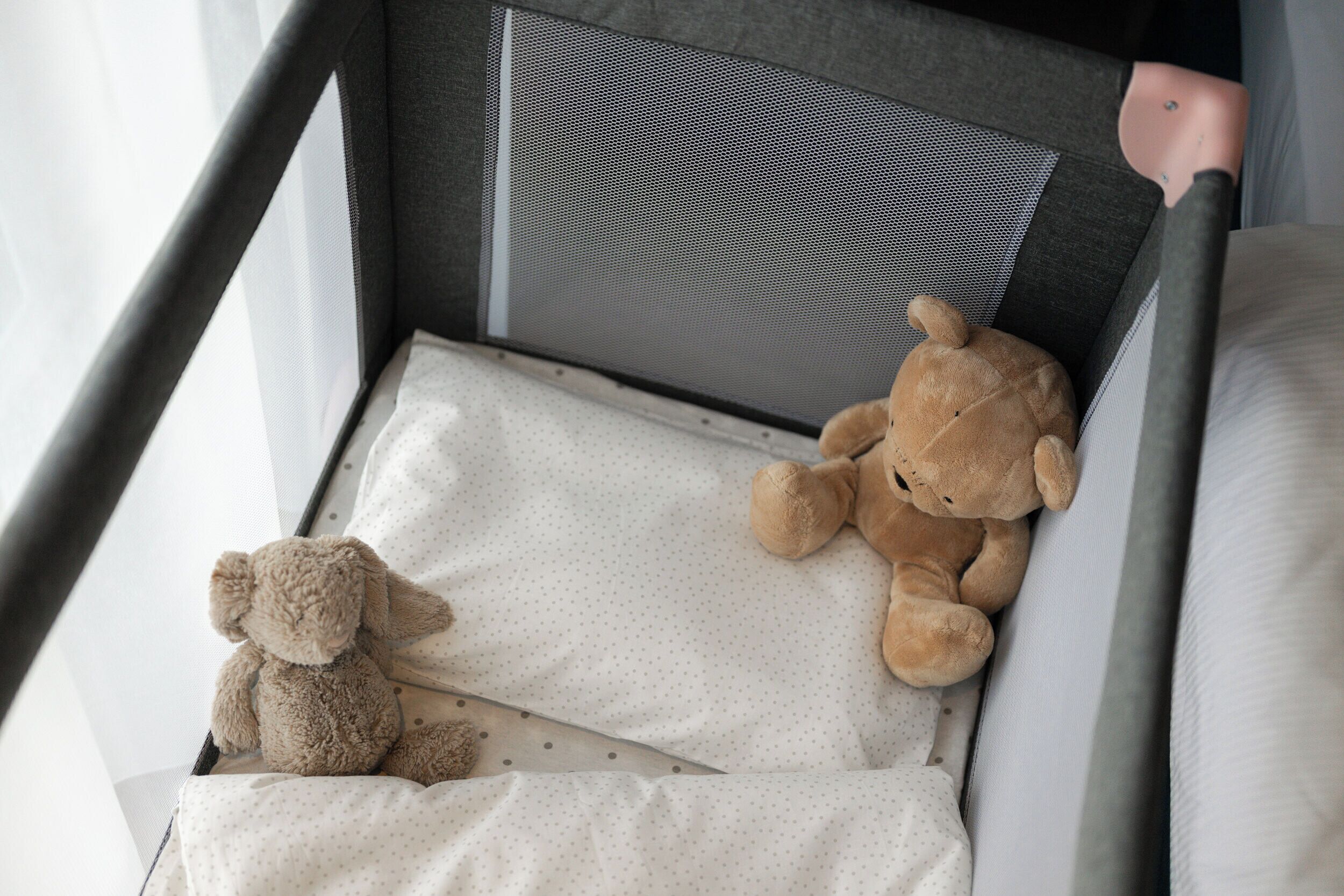 A crib with a mattress and a stuffed bear.
