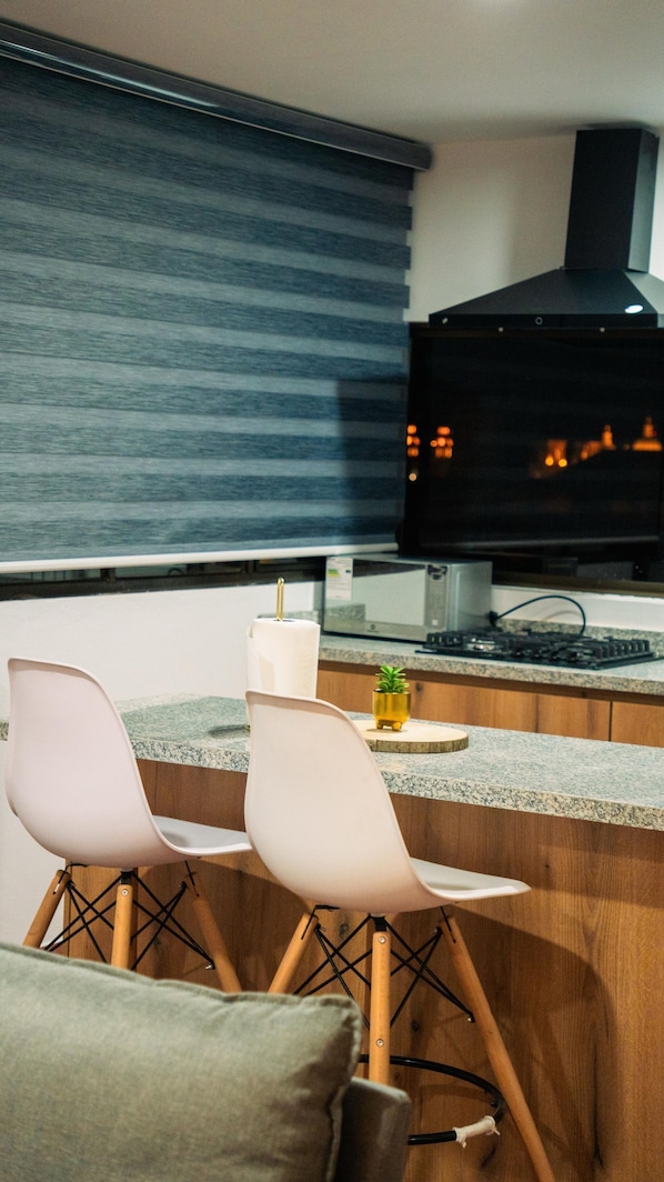 A modern kitchen with two white chairs, a small plant, and a microwave.