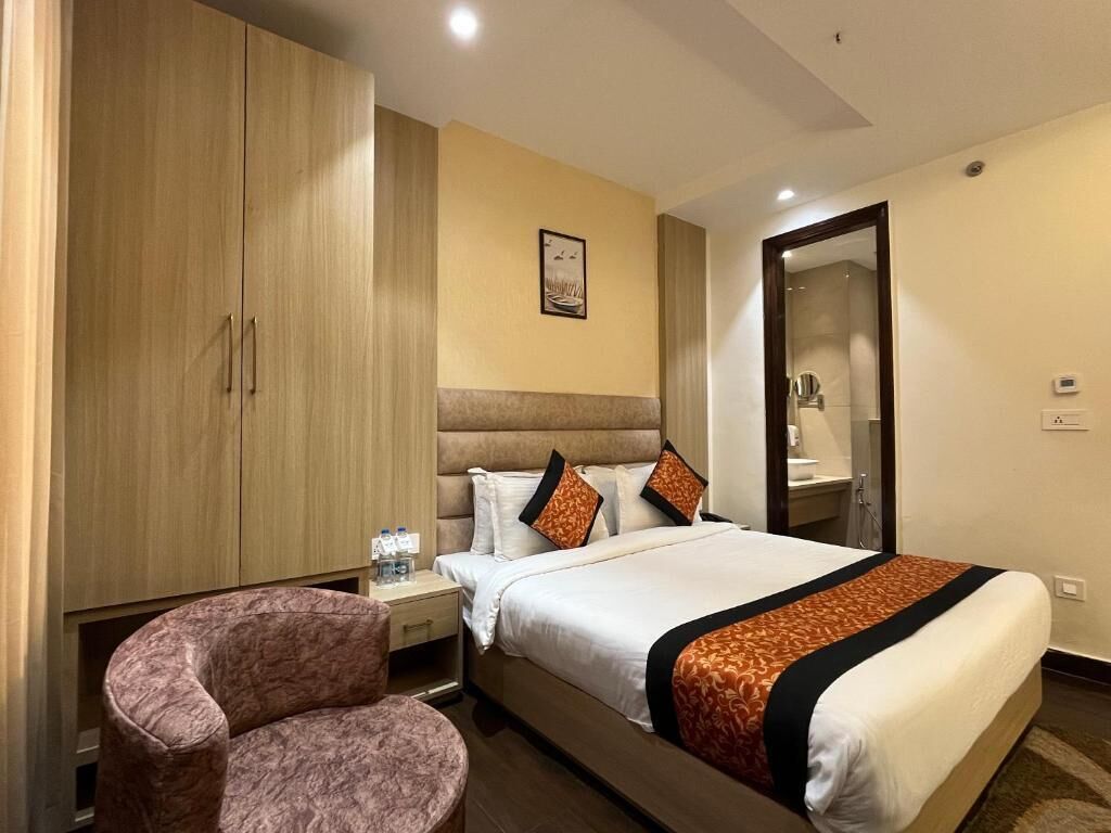A hotel room with a bed, a wardrobe, a nightstand, and a chair.