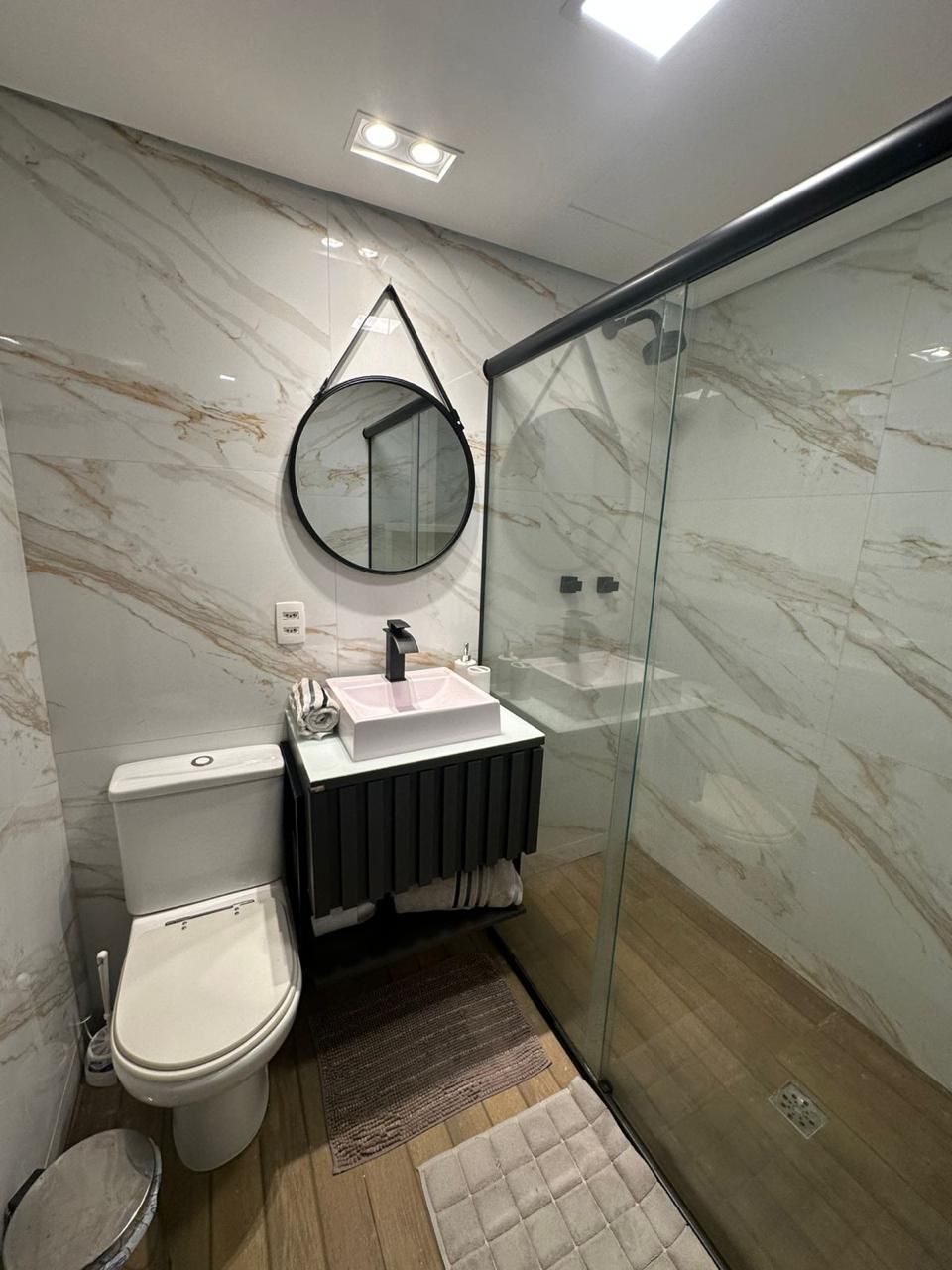 A modern bathroom with a toilet, sink, and glass shower enclosure.