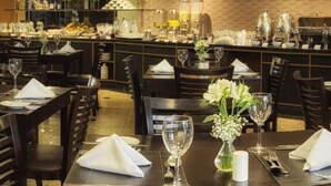 Een restaurant met meerdere tafels, elk voorzien van witte servetten, wijnglazen en bestek.