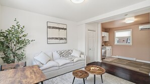 A modern living room with a sofa, coffee table, and a dining table. There is a potted plant and a painting on the wall. - 5 mins walk from The Harbour, The Rooms, and all the fun of Downtown St. John’s! (St. John's)