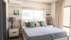 Un dormitorio con cama, mesitas de noche y ventana con cortinas.
