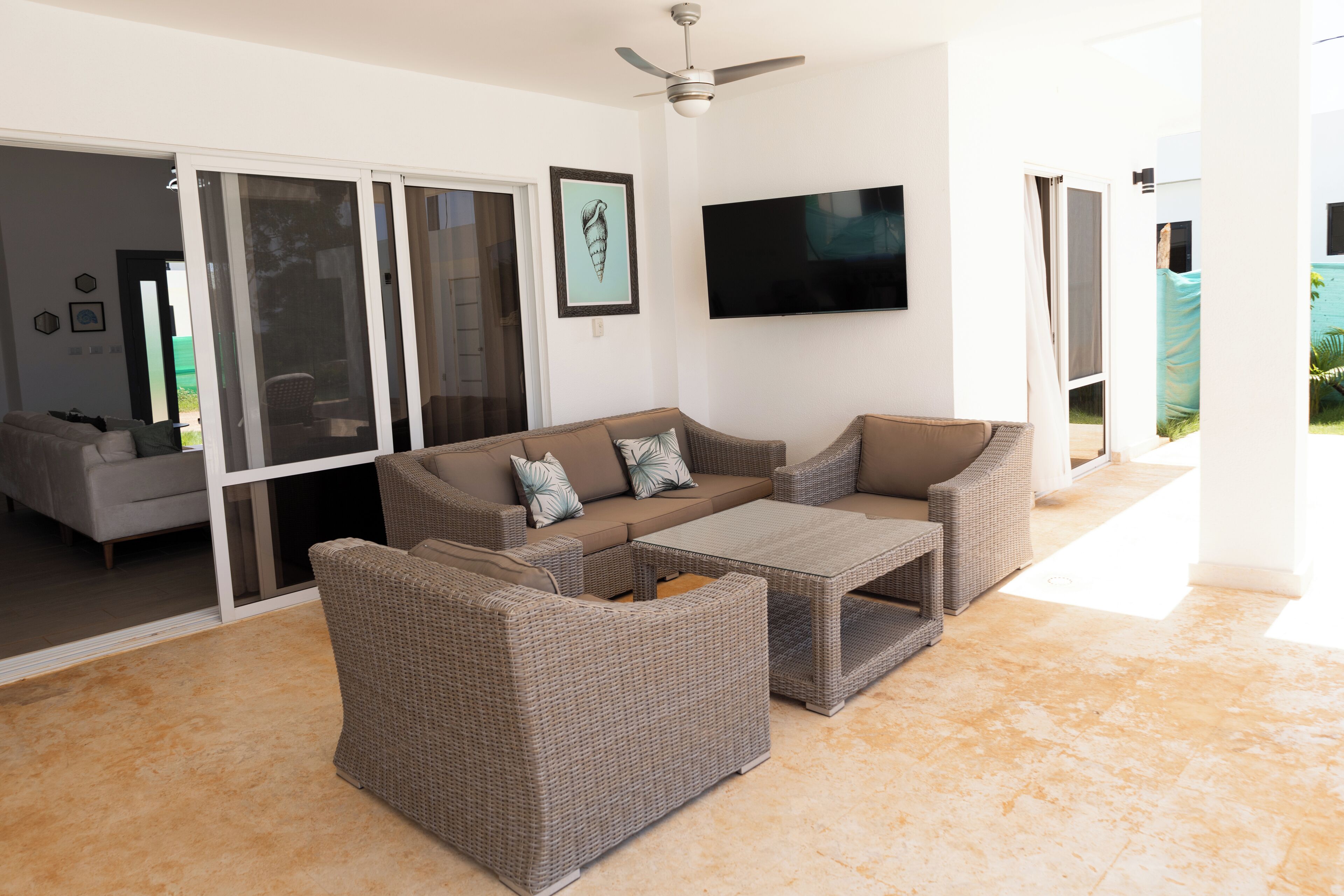 A living room with a sofa set, a coffee table, and a flat-screen TV mounted on the wall.