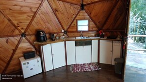 A cozy, wooden-paneled room with a built-in kitchen area, including a refrigerator, a coffee maker, and a sink.