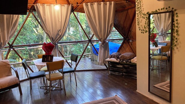 A cozy, wooden-paneled room with a dining area, a sofa, and a TV mounted on the wall.
