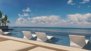 A poolside area with lounge chairs and a view of the ocean. - The Pyrmont Curaçao, An Autograph Collection, All-Inclusive Resort Adults Only (Willemstad)
