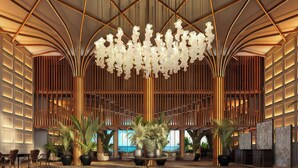 A spacious lobby with a modern chandelier, large potted plants, and a patterned floor. - The Pyrmont Curaçao, An Autograph Collection, All-Inclusive Resort Adults Only (Willemstad)