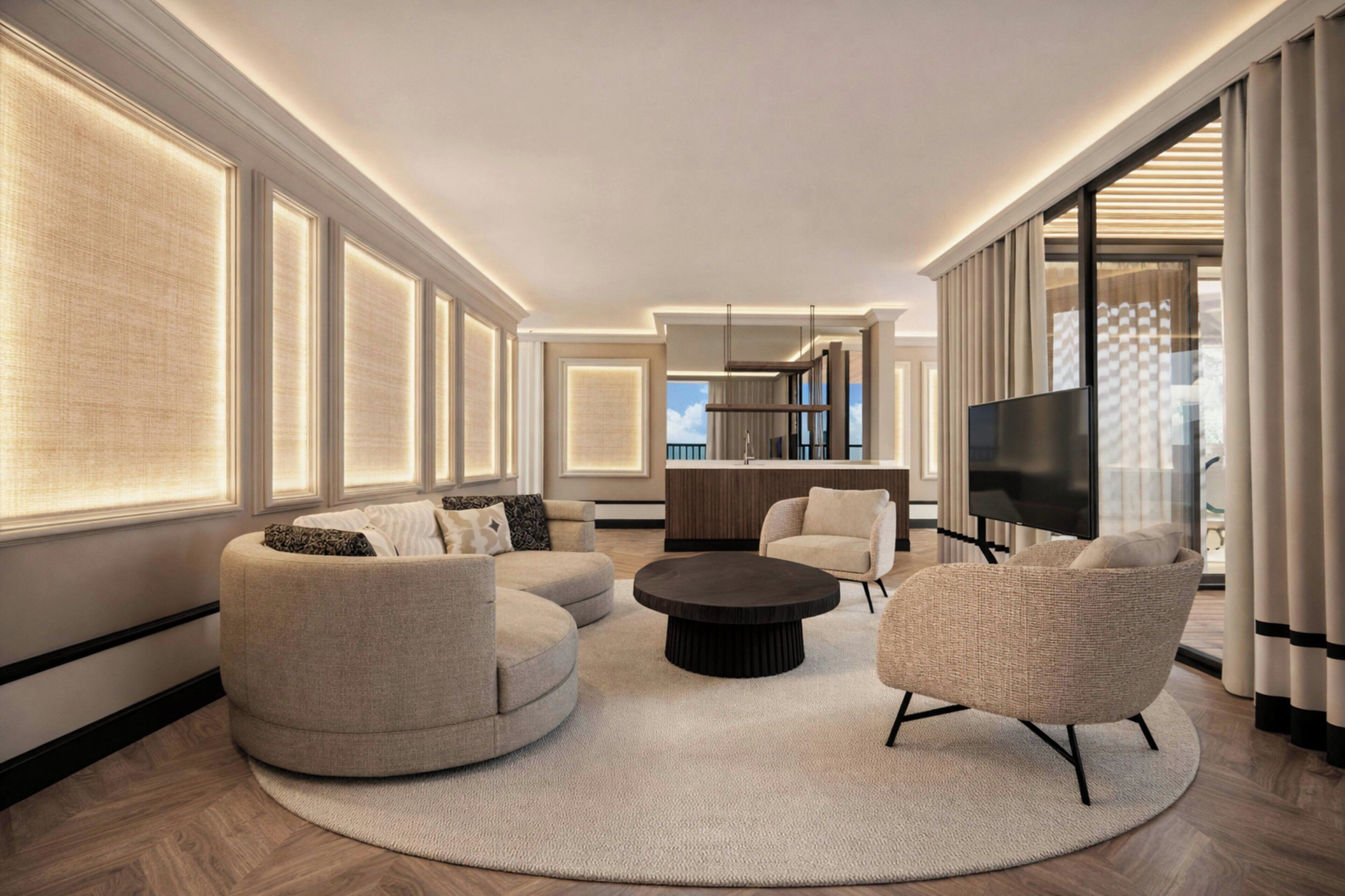 A modern living room with a round coffee table, two sofas, a TV, and a kitchen area in the background.