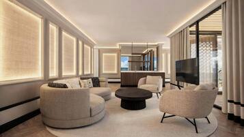 A modern living room with a round coffee table, two sofas, a TV, and a kitchen area in the background.