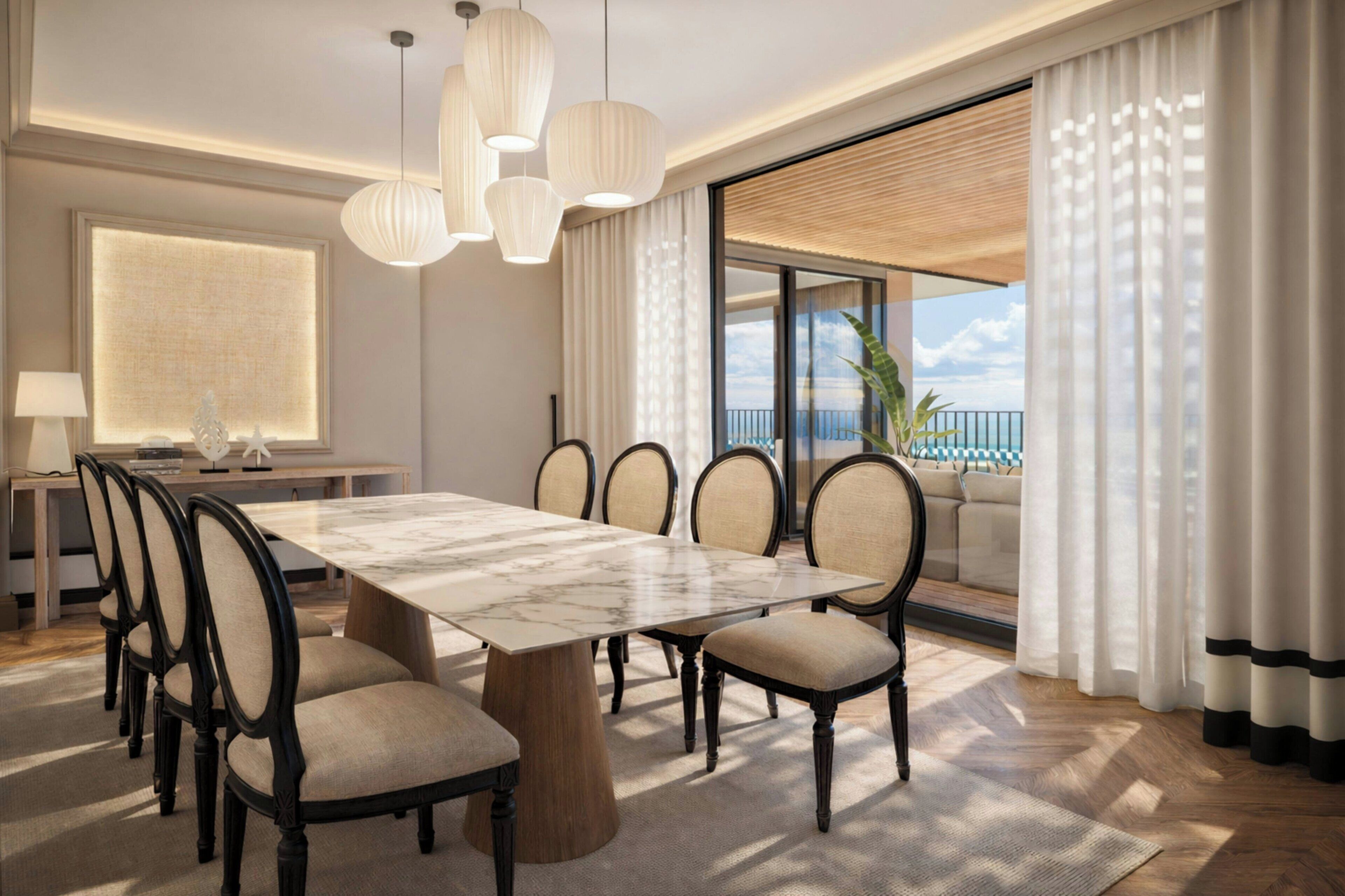 Comedor moderno con una mesa de mármol, sillas tapizadas e iluminación colgante.