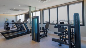 Una palestra moderna con tapis roulant, macchinari per pesi e vista su un paesaggio innevato attraverso ampie finestre.