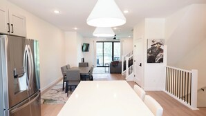 A modern kitchen with a large island, stainless steel appliances, and a dining area with a white table and chairs. - NashLo Boji Retreat (Arnolds Park)