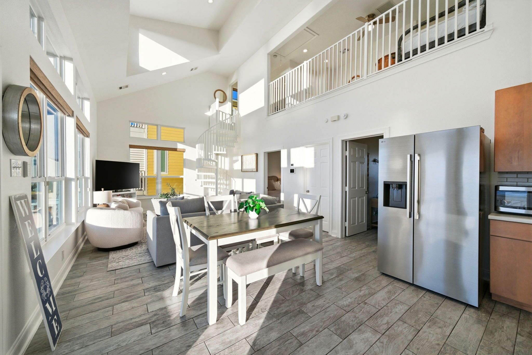 A spacious kitchen with a large island, stainless steel appliances, and a dining area with a high ceiling and natural light.