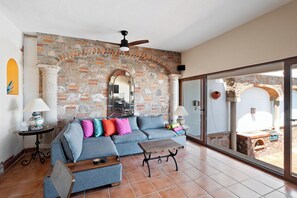Ein Wohnzimmer mit Backsteinwand, einer Couch, einem Couchtisch und Blick durch eine Glastür.