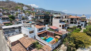 A residential area with multiple buildings, a swimming pool, and a hilly landscape in the background. - 4BR Private Oceanview Retreat, Steps from Malecon & Zona Romantica (Puerto Vallarta)