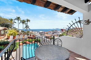 A balcony with a pool, outdoor seating, and a view of the sea and cityscape. - 7BR Oceanview Retreat with Pools & Hot Tub in the Heart of PV's Historic Centro (Puerto Vallarta)