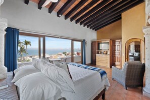 A bedroom with a large bed, a view of the sea, and a balcony with a table and chairs. - 7BR Oceanview Retreat with Pools & Hot Tub in the Heart of PV's Historic Centro (Puerto Vallarta)