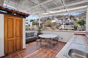 Eine Terrasse mit Holztür, einer Couch, einem runden Tisch und Stühlen.
