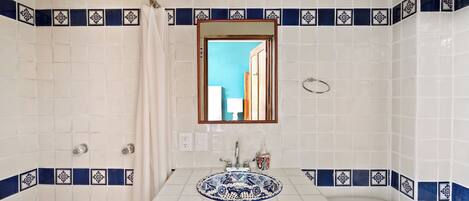 A bathroom with a white sink, blue decorative tiles, a mirror, and a shower.
