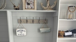 Una habitación con estante de madera, un cuadro enmarco, objetos decorativos y un zapatero.