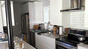 Una cucina moderna con elettrodomestici in acciaio inossidabile, mobili bianchi e un piano di lavoro grigio.