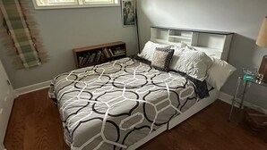 Camera da letto con un letto, un comodino, una lampada, una finestra e una mensola a parete.