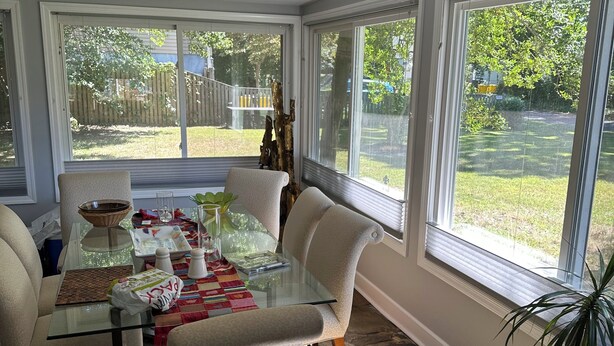 Una veranda con tavolo e sedie in vetro, e vista sul giardino.