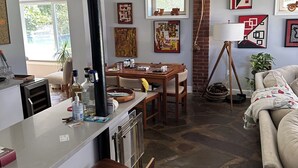 Una cucina moderna con isola centrale, un'area pranzo con tavolo e sedie, un soggiorno con divano e opere d'arte alle pareti.