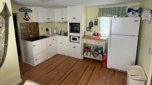 Una cocina compacta con armarios blancos, estufa a gas, horno, microondas y refrigerador.