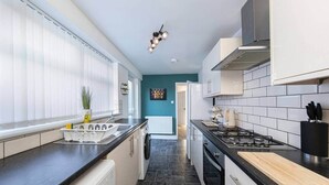 Een moderne keuken met zwarte aanrechtbladen, witte kastjes, een fornuis en een vaatwasser.