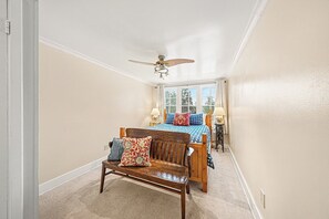 Une chambre à coucher avec un lit en bois, un banc et un ventilateur de plafond.